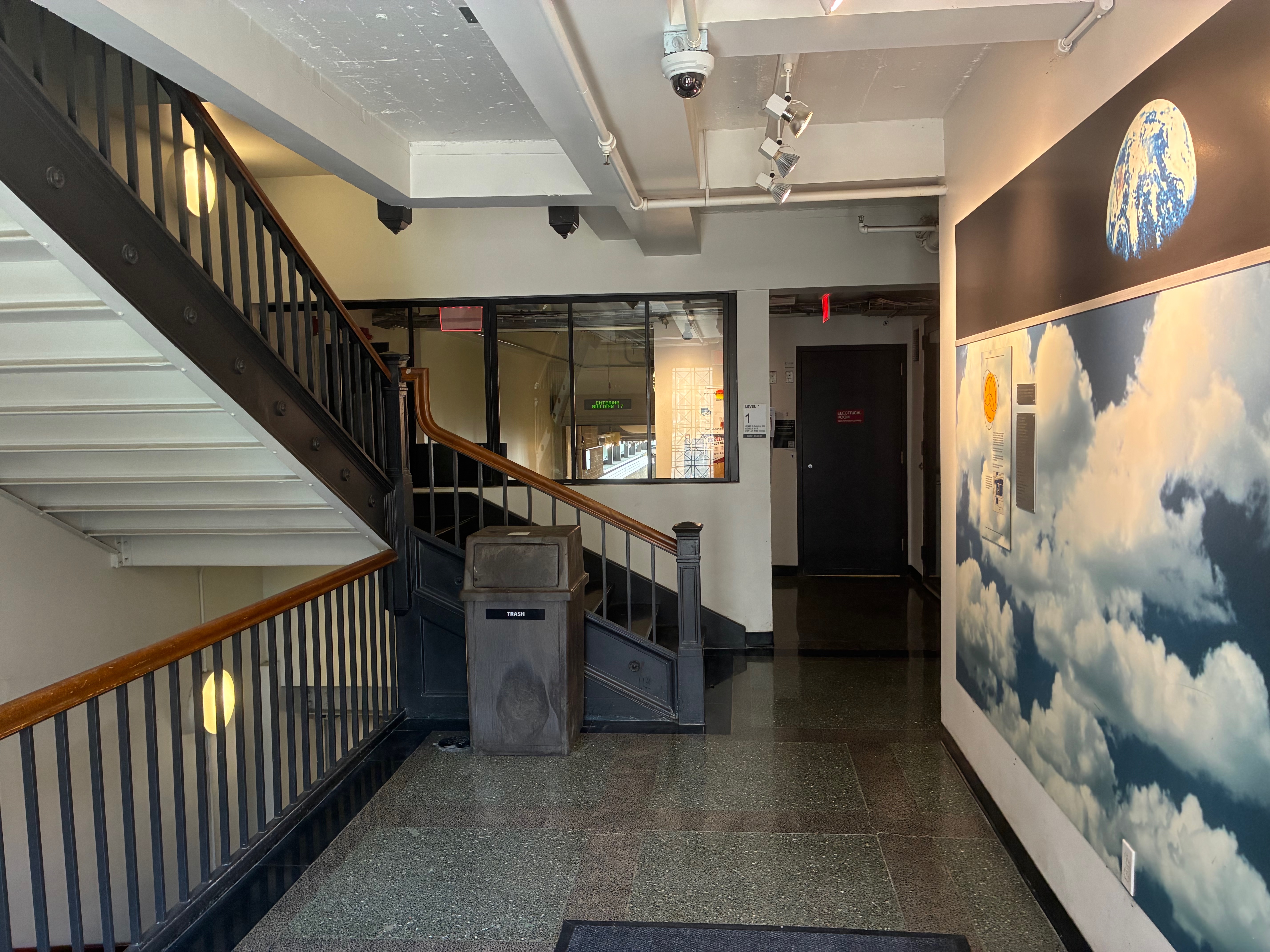 Interior lobby with a sky-and-clouds mural beside a staircase